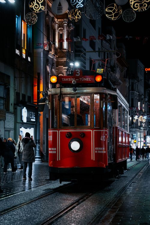 Free Nighttime scene of a historic red tram on Istanbul's bustling Istiklal Street with people and city lights. Stock Photo