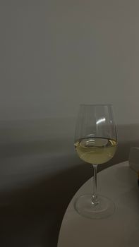 A close-up photo of a wine glass with white wine on a minimalist table, perfect for lifestyle concepts.
