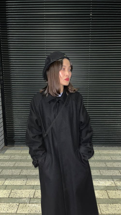 Woman in Black Coat Standing with Hands in Pockets