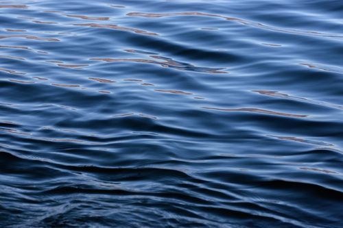 Free Calm ocean waves create a soothing ripple texture under a clear sky. Stock Photo