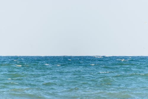 Free Serene view of the calm ocean and blue sky meeting at the horizon line. Stock Photo