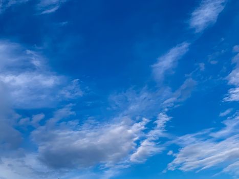 A clear blue sky with scattered wispy clouds, ideal for a serene backdrop or wallpaper.