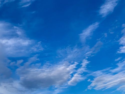 Free A clear blue sky with scattered wispy clouds, ideal for a serene backdrop or wallpaper. Stock Photo