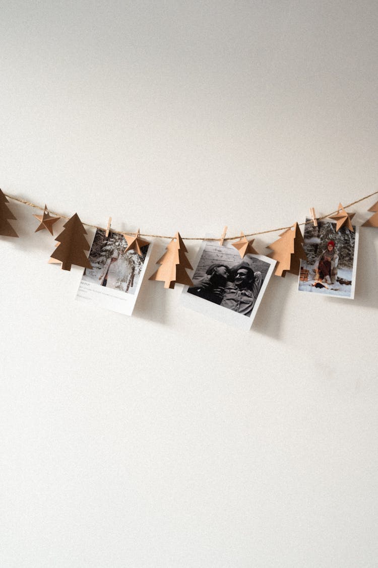 Photos And Christmas Tree Cutouts Hanging On A Line On A Wall 