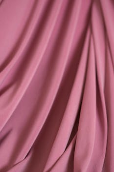 A close-up of soft pink fabric showcasing elegant drapery folds for design and texture inspiration.
