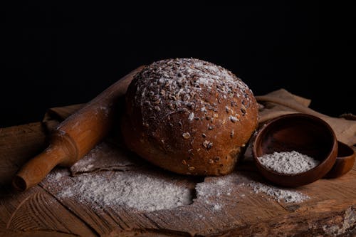 A Freshly Baked Bread Lying on the Table with Flour and a Rolling Pin 