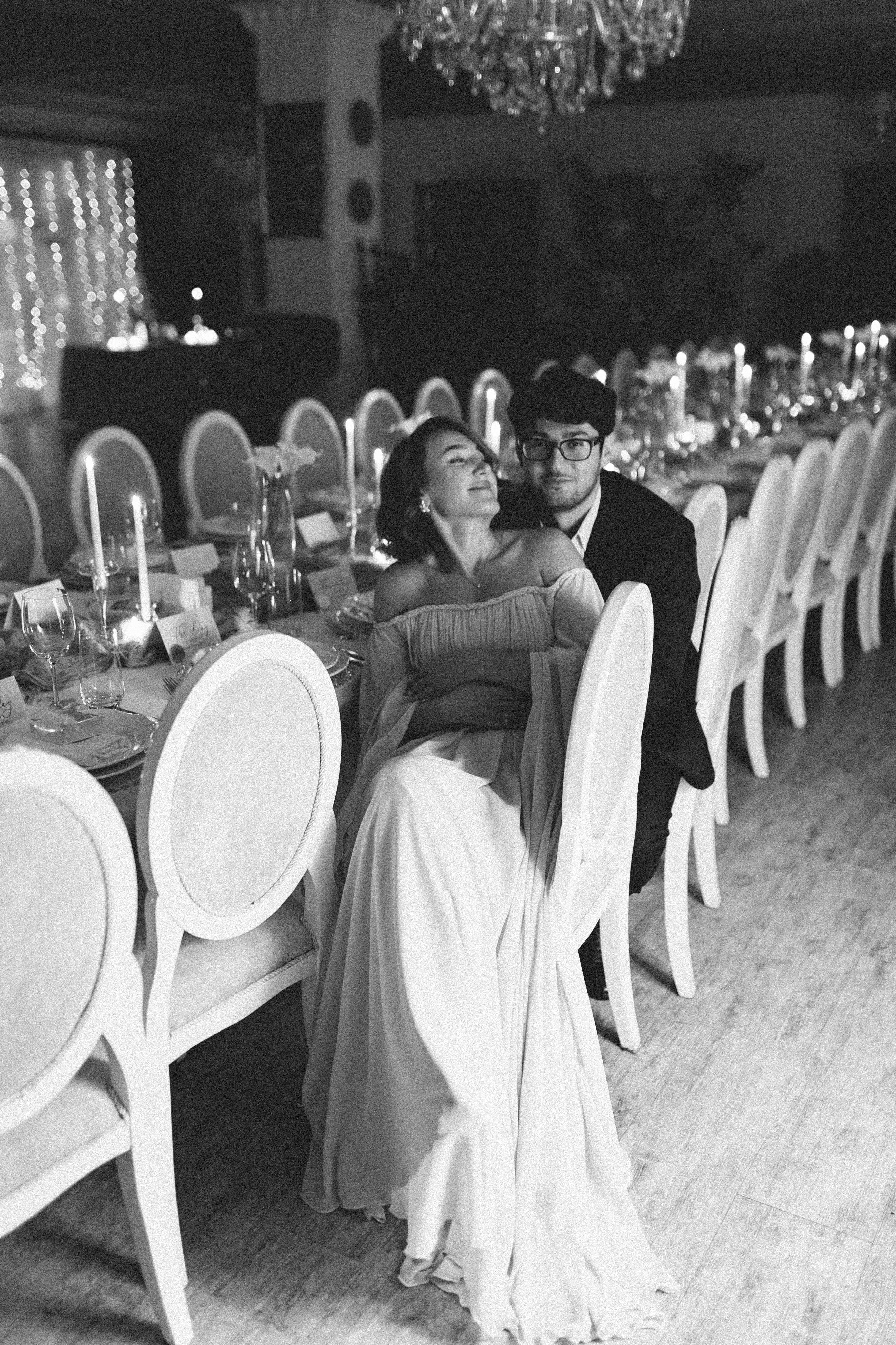 Black and white photo of a couple seated closely at a formal event, highlighting elegance and intimacy.
