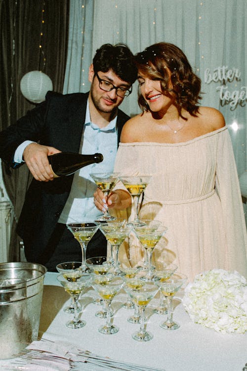 Groom Pouring Champagne in Wineglasses at Party