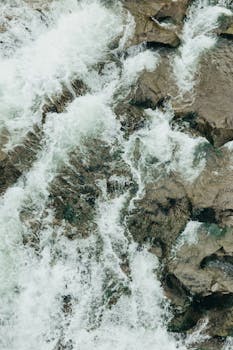 Aerial shot capturing the powerful flow of a waterfall over rocks.
