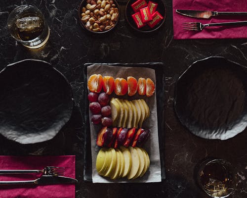 Fruit on Tray with Bowls with Nuts and Chocolates near