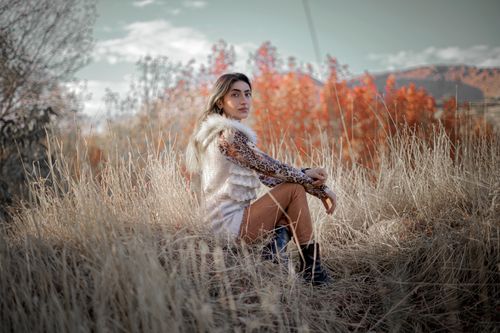 Free A woman posing in a grassfield with autumn colors, showcasing fashion photography. Stock Photo