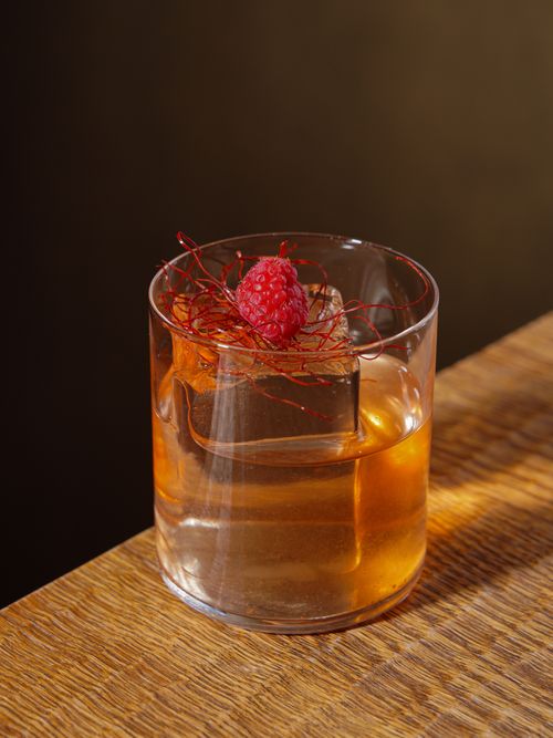 Free A sophisticated cocktail with raspberry garnish on a wooden table, perfect for food photography. Stock Photo