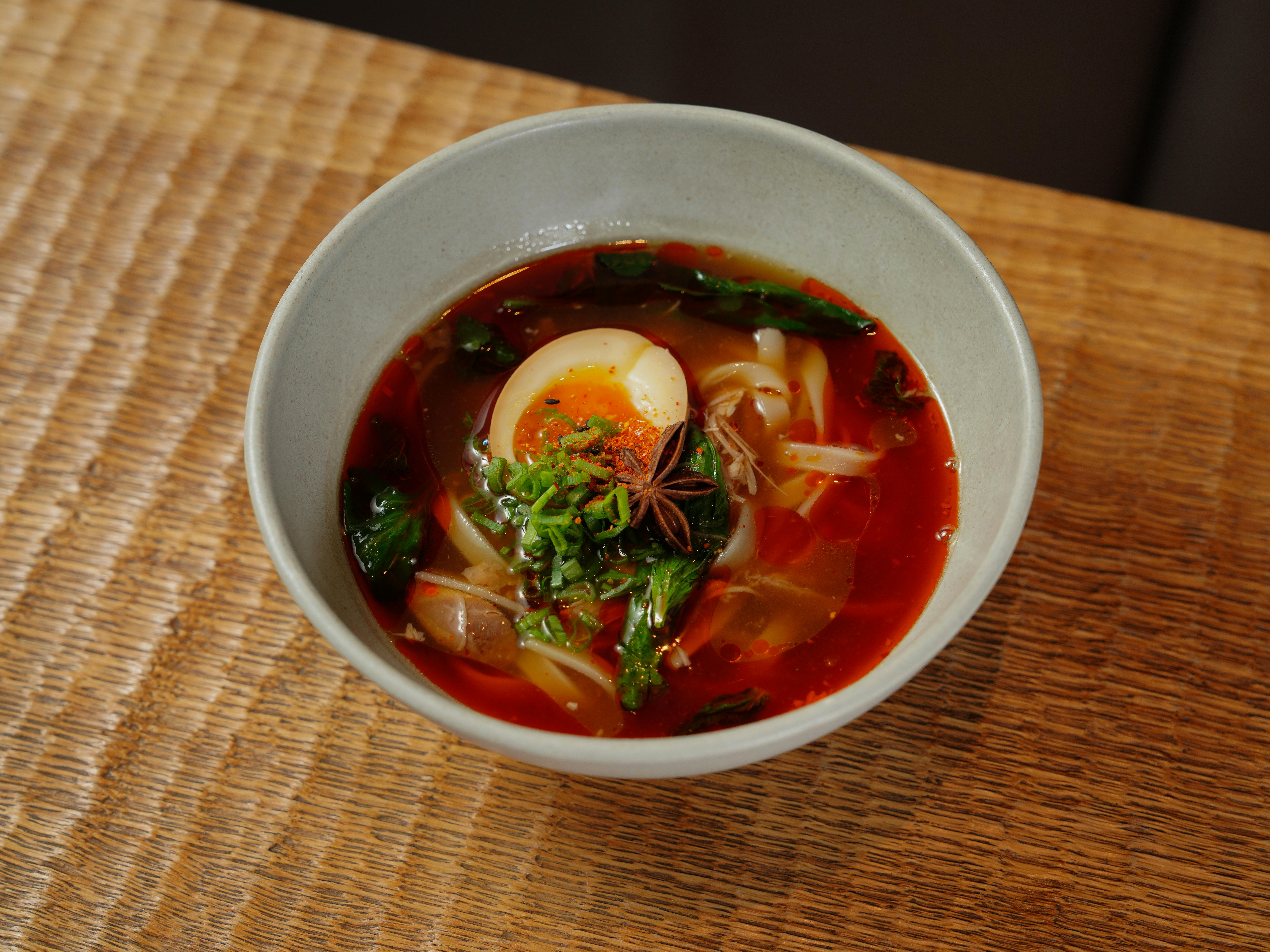 Delicious bowl of spicy ramen topped with egg, greens, and star anise.