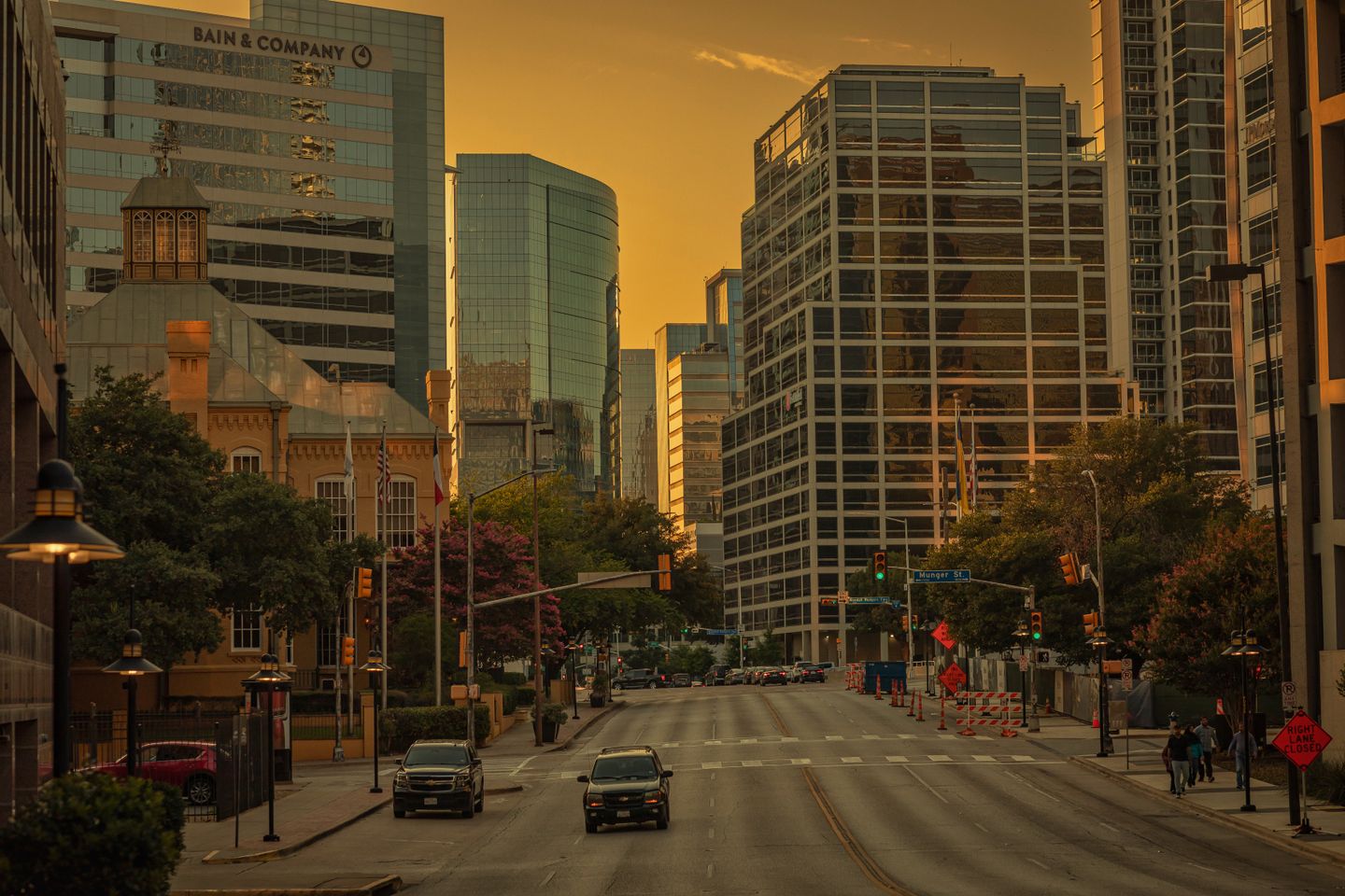 Golden hour street view of Dallas Uptown with modern high-rise buildings, historic architecture, and tree-lined street