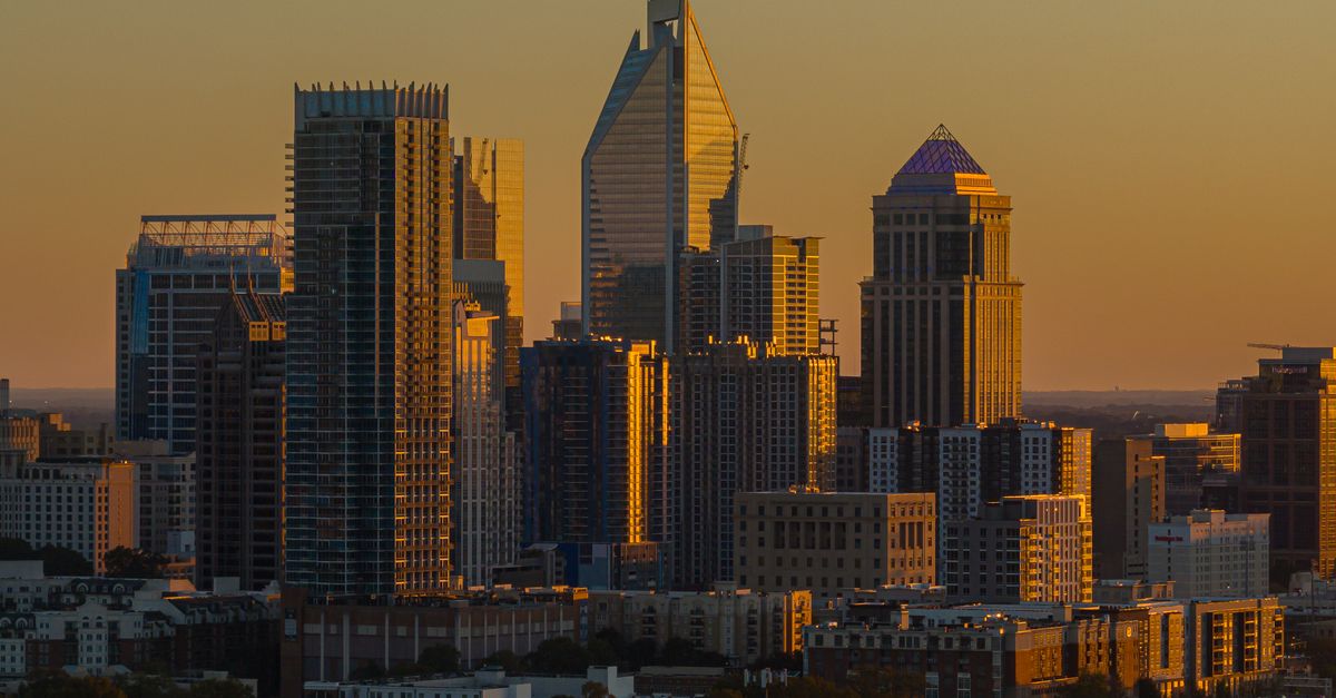 Dramatic sunset highlights Charlotte's modern skyline with striking skyscrapers and urban architecture.