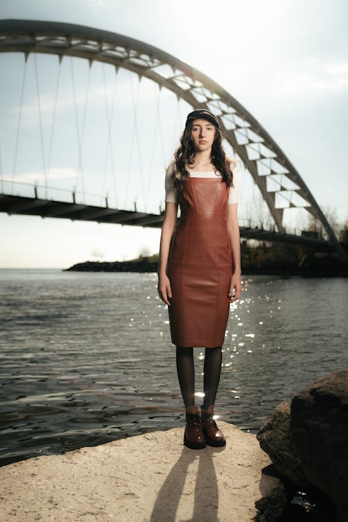 A woman in a leather dress stands by the water