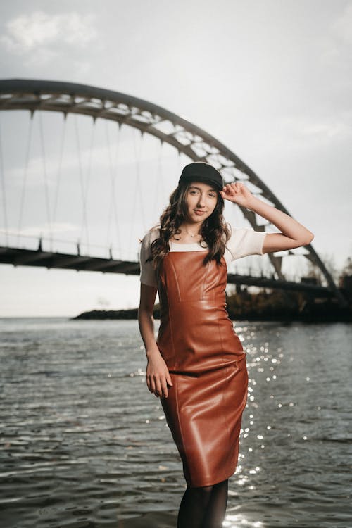 A woman in a leather dress posing by the water