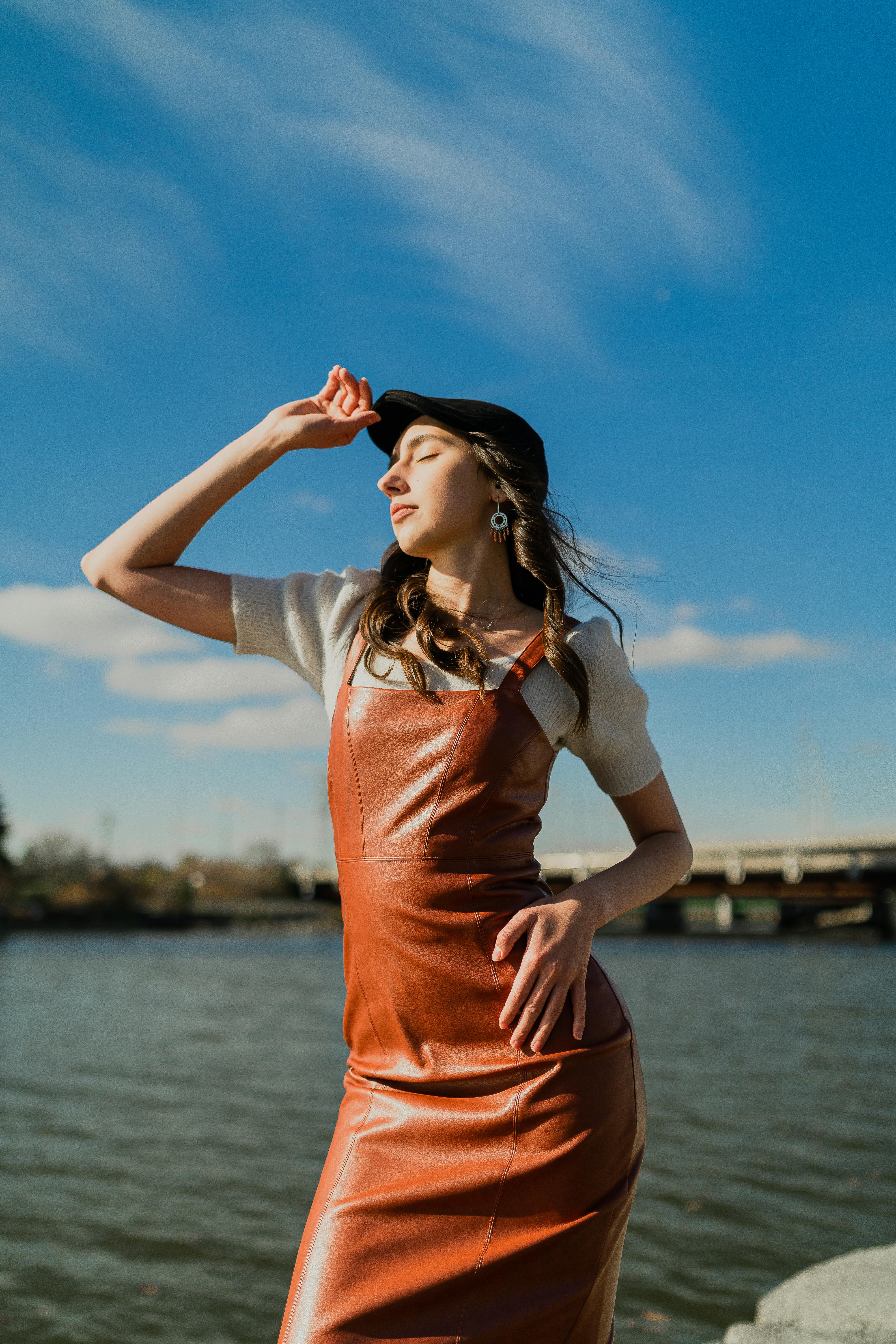 a woman in an orange leather dress and hat