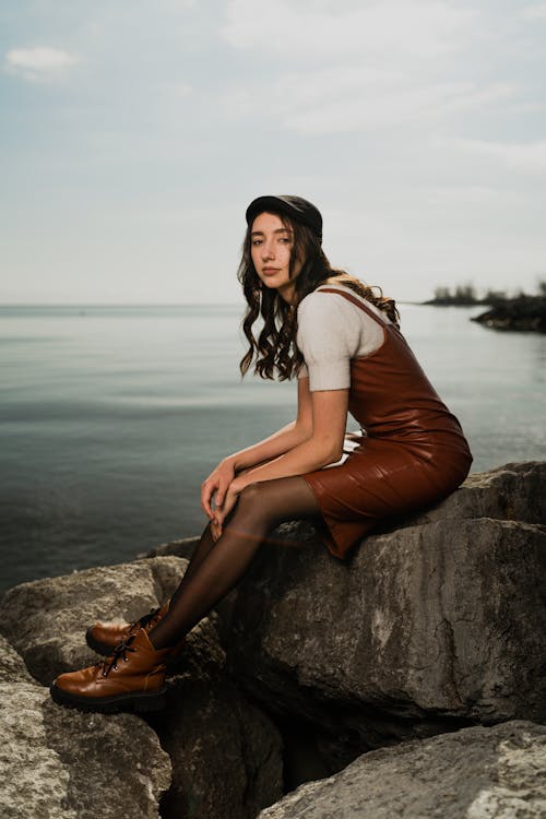 A woman in a leather dress sitting on a rock