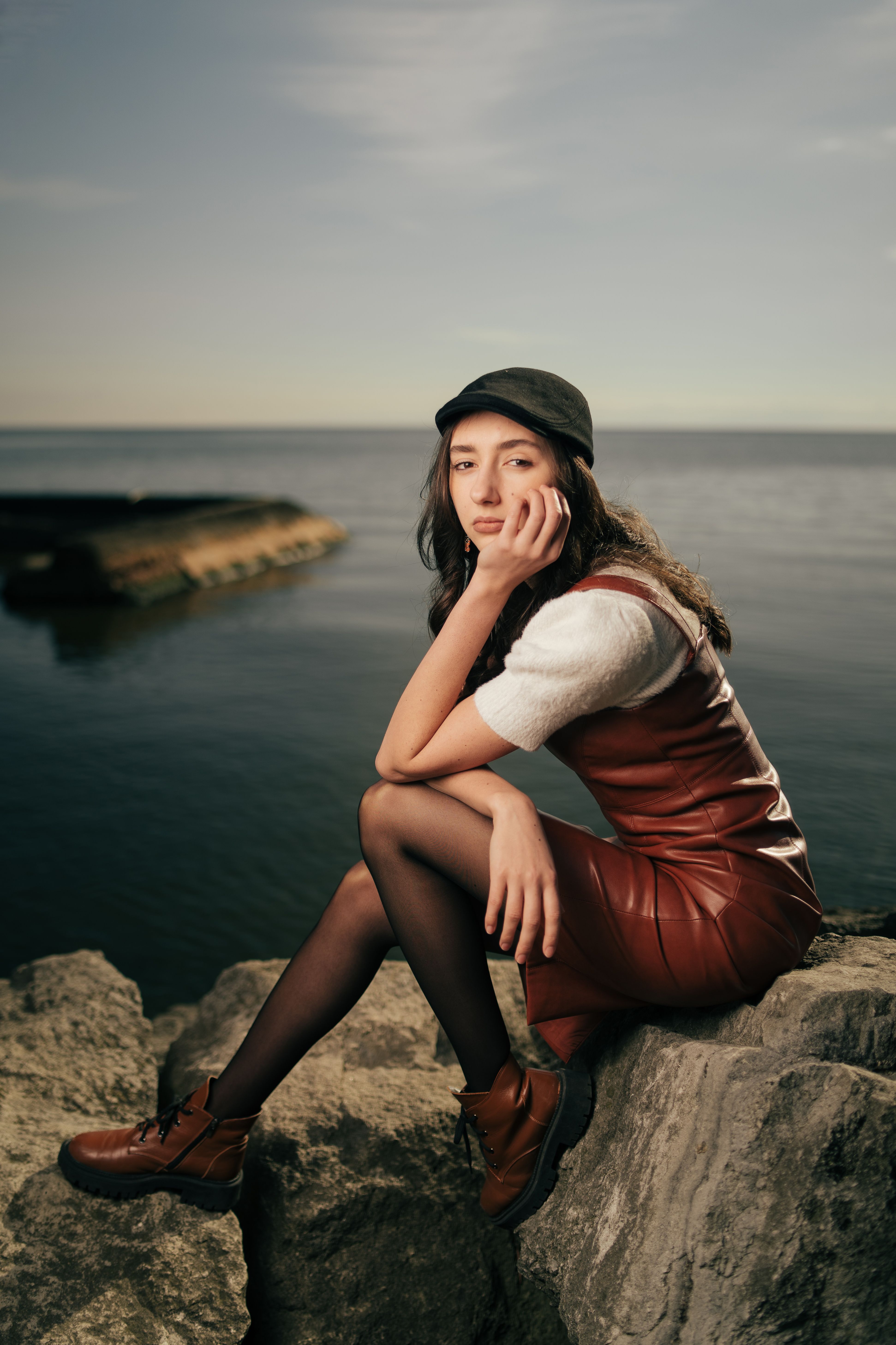 A woman in a red dress and hat sitting on rocks · Free Stock Photo