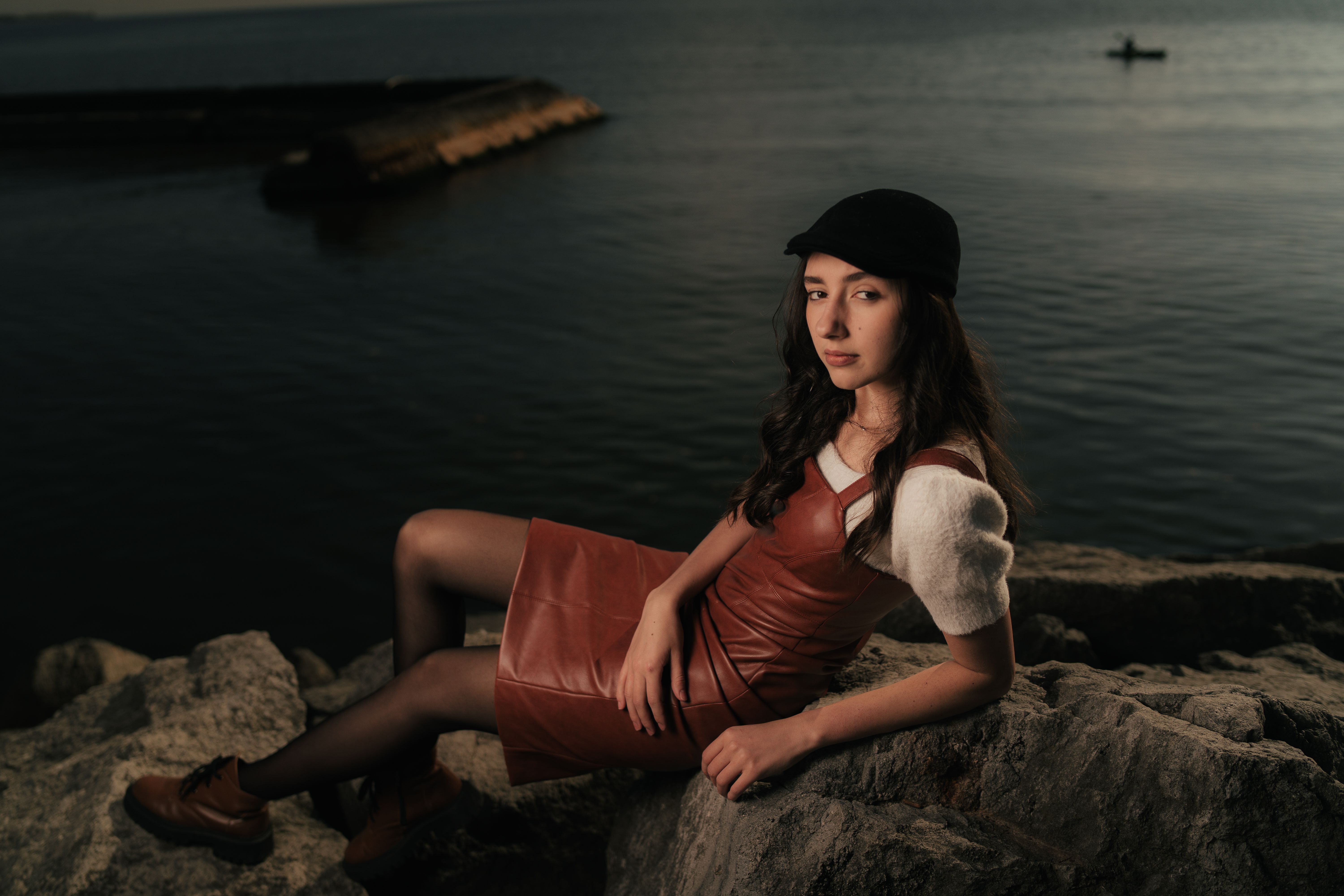 A woman in a hat and dress sitting on rocks · Free Stock Photo