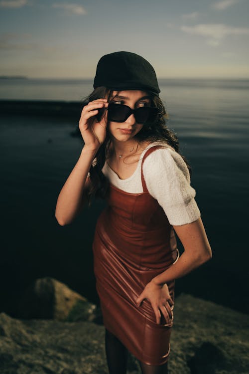 A woman in a leather dress and hat by the water