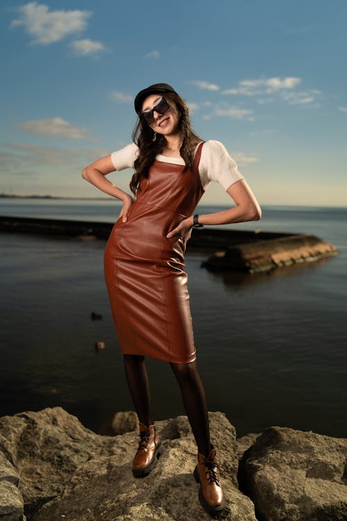 A woman in a brown leather dress posing on the rocks