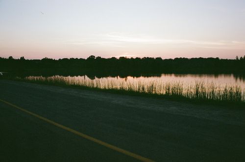 Free Serene sunset over a lakeside with distant trees and calm waters. Stock Photo