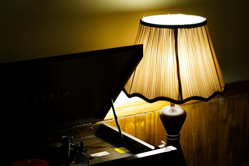 A dimly lit vintage setup featuring a gramophone and a warm glowing table lamp.