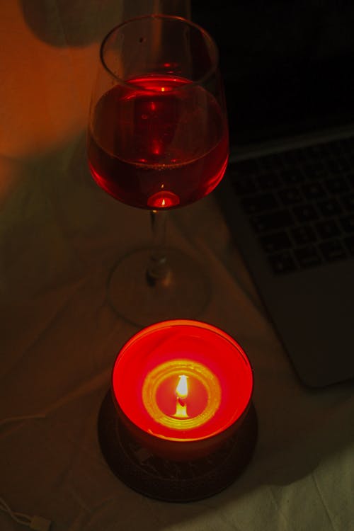 Glass of Red Whine Next to a Candle 