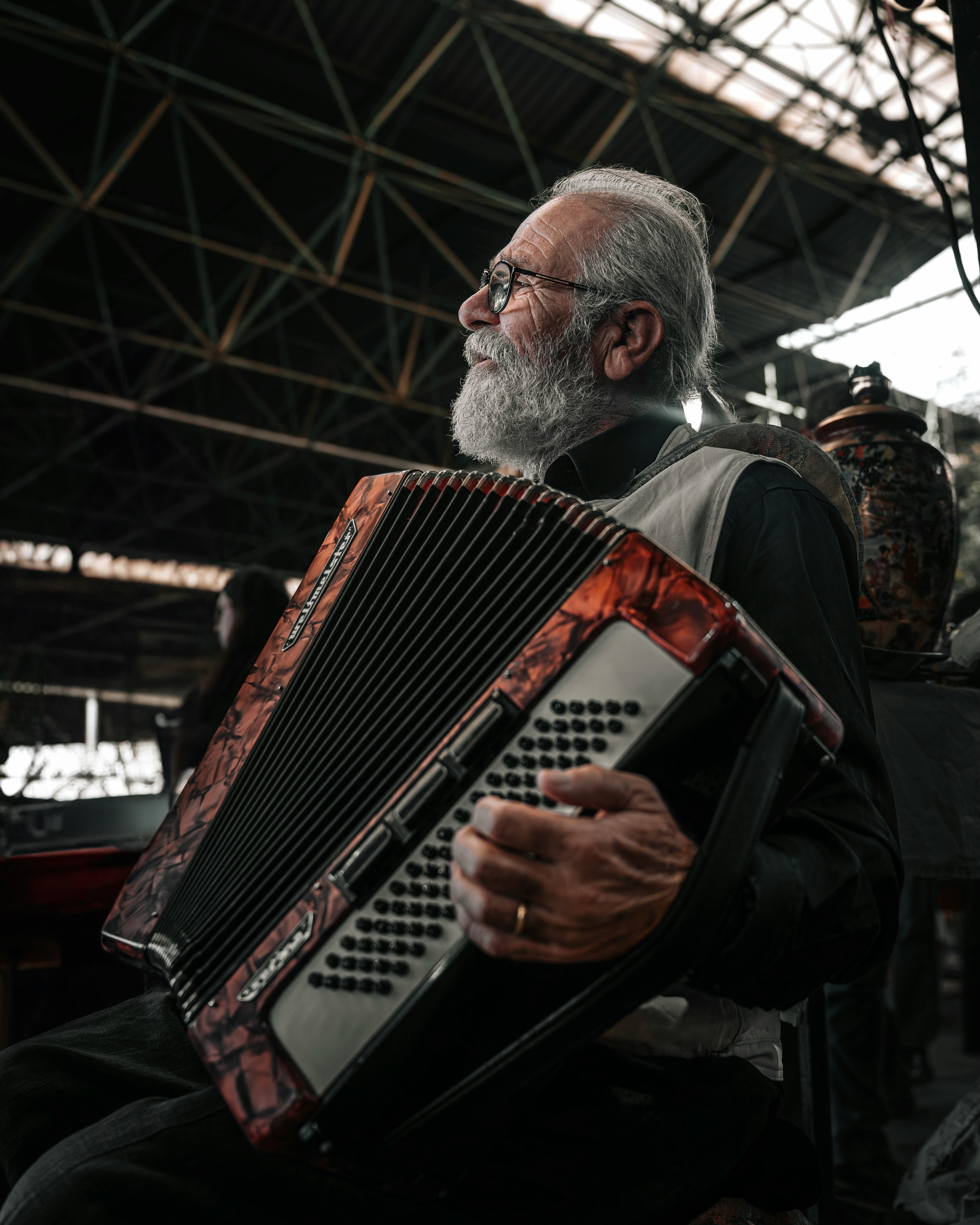 A senior man playing accordion indoors in Ankara, Turkey. Capturing musical passion.