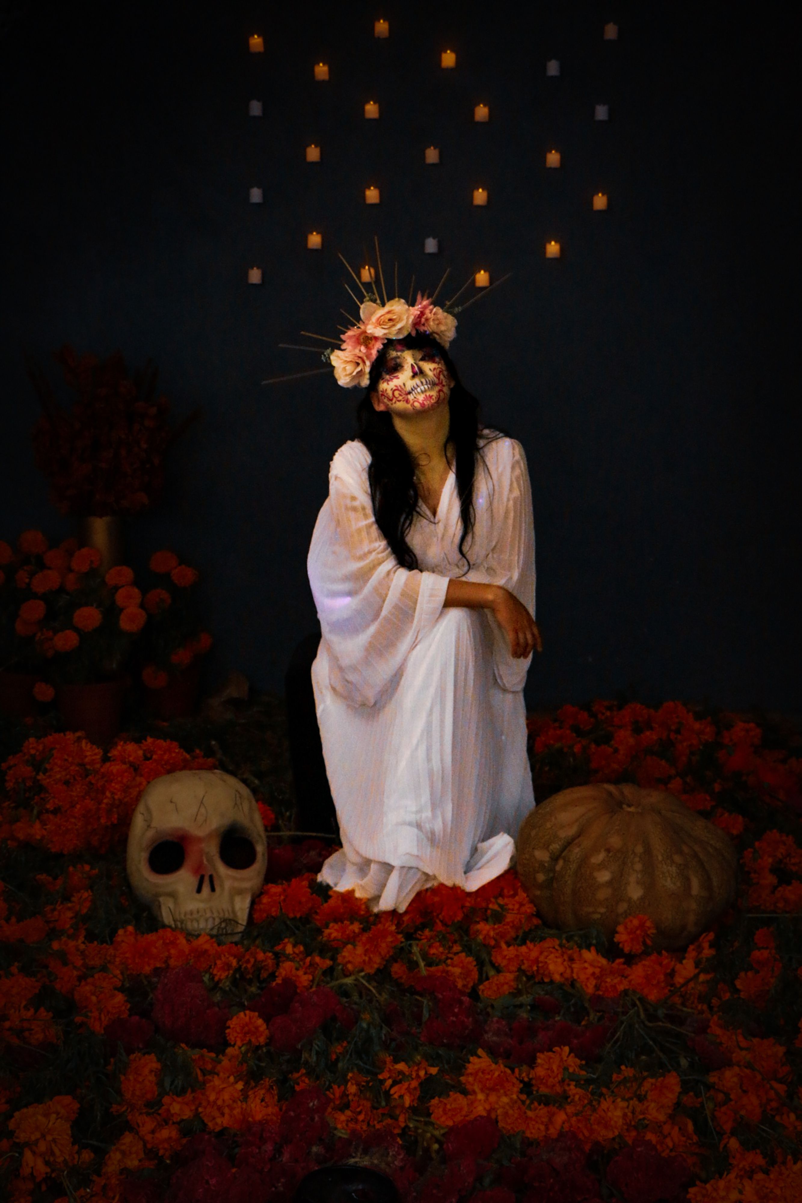 Fotomural Mujer en traje tradicional del Día de Muertos con tocado floral y pintura facial de calavera.