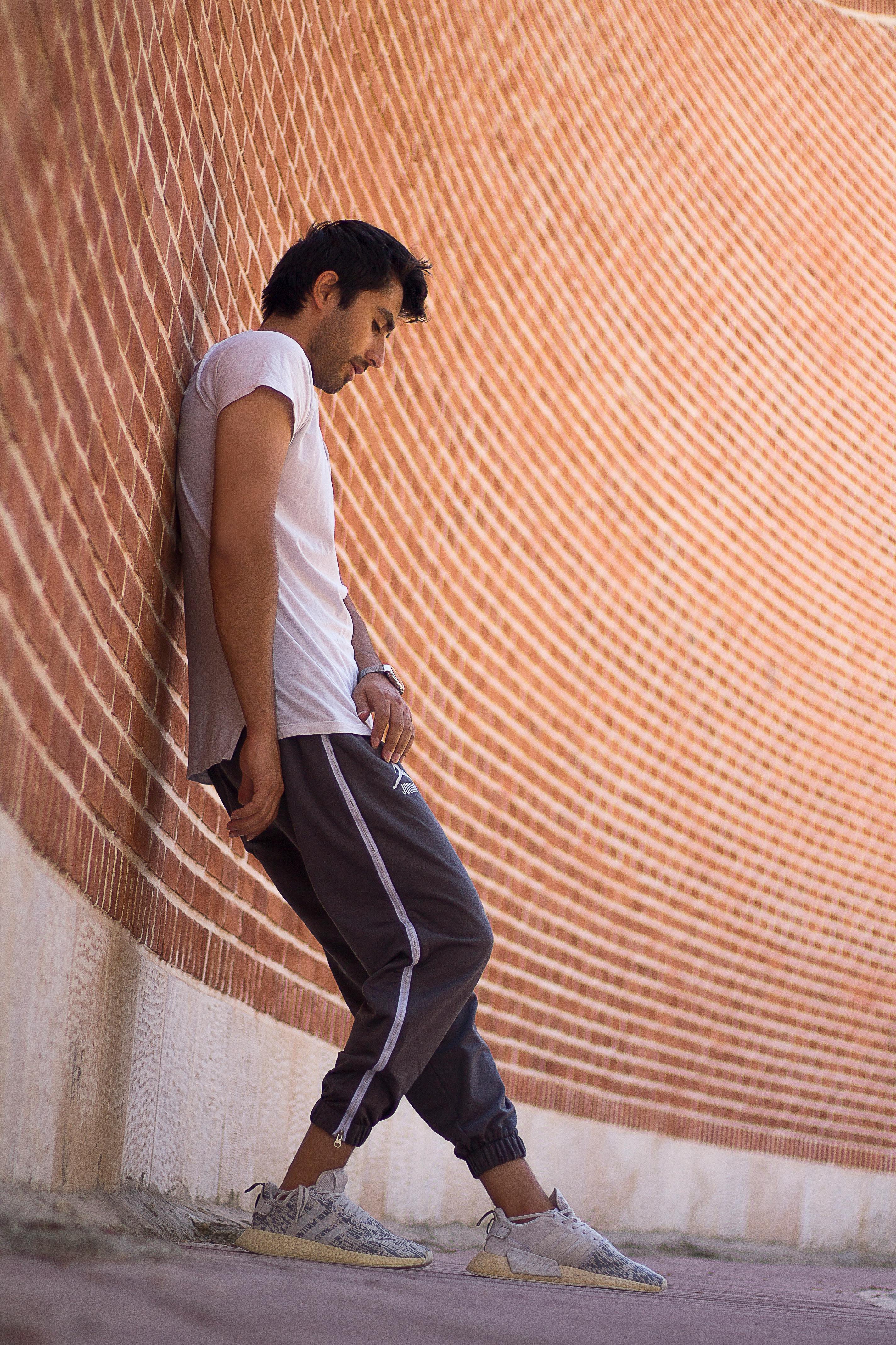 Young Man in a Casual Outfit Standing with His Back against the Wall