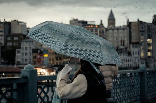 Free Woman with umbrella on a rainy day in Istanbul, view of Galata Tower in the background. Stock Photo