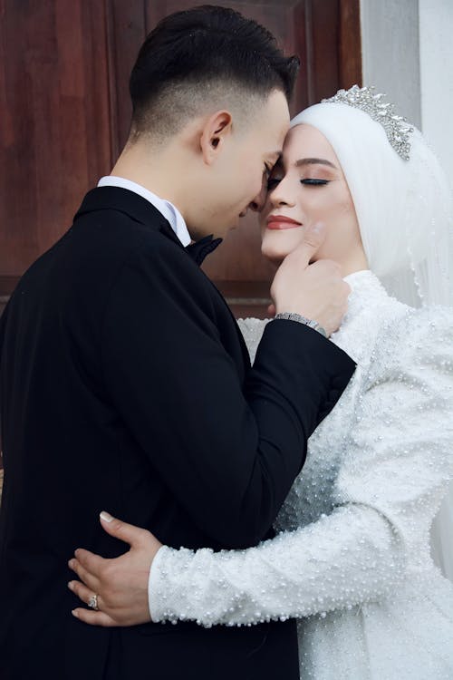 A man and woman in wedding attire hugging