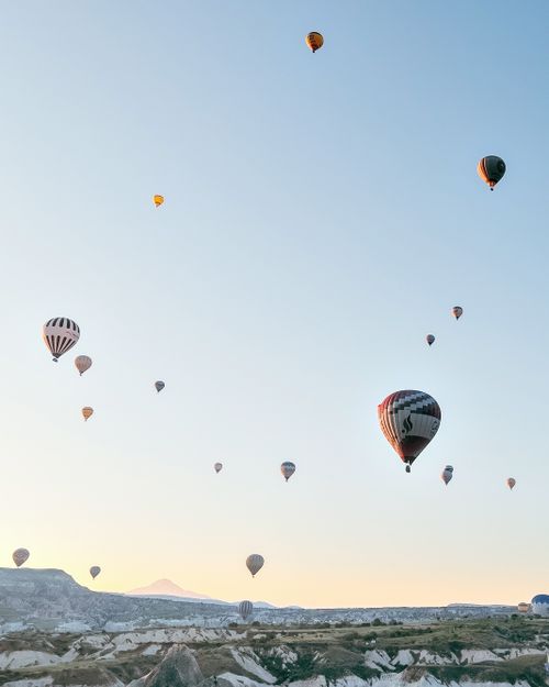 Free Scenic view of hot air balloons floating over Cappadocia's unique landscape during sunrise. Stock Photo