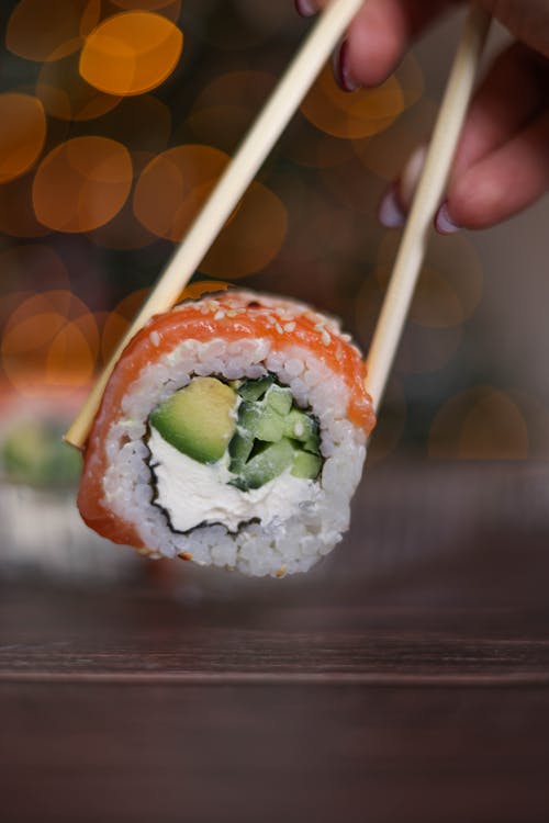 Close-up of a Piece of Sushi Held between the Chopsticks 