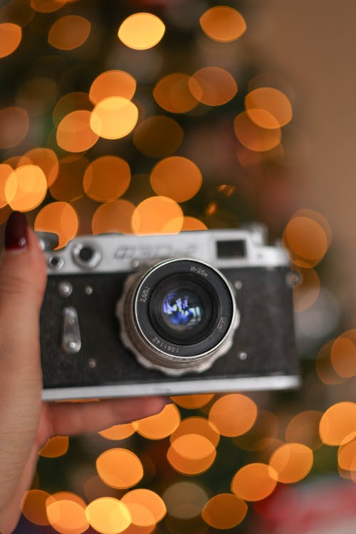 Close-up of Woman Holding a Film Camera on the Background of a Christmas Tree