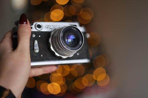 Close-up of Woman Holding a Film Camera on the Background of a Christmas Tree