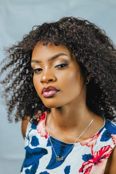 Stunning studio portrait of a young woman with curly hair and floral dress, exuding confidence.