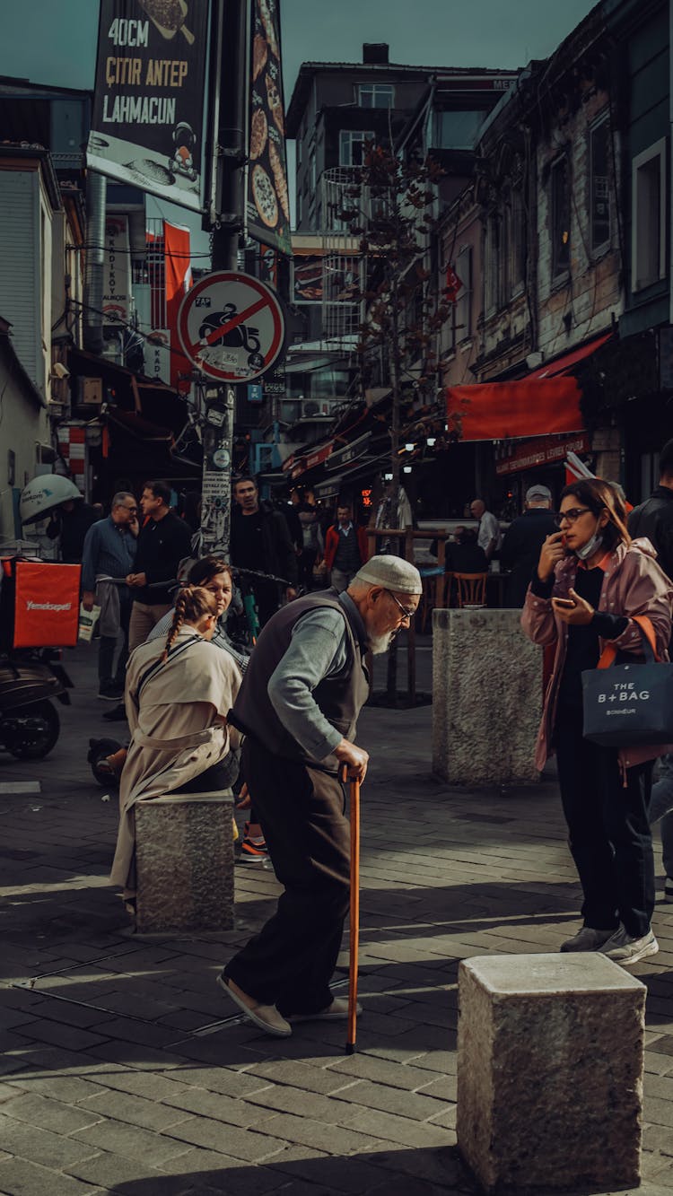 Hunched Elderly Man With Cane In City