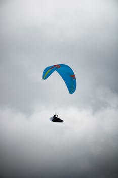 A lone paraglider navigating the cloudy skies of Hintertux, Tirol, Austria, showcasing adventure.