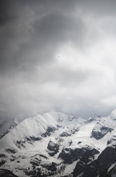 Majestic view of the Tux Alps in Tirol, Austria, with snow-covered peaks and a dramatic sky.