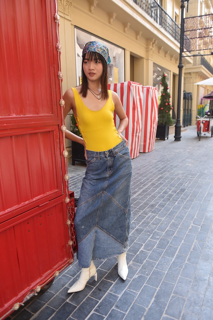 Model In A Yellow Bodysuit And A Denim Skirt In Front Of A Cafe