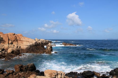 Free Captivating view of rocky coastline meeting the ocean under a bright blue sky. Stock Photo