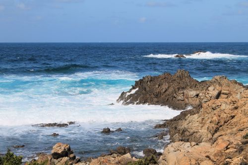 Free Beautiful rocky coastline meeting the blue ocean waves under a clear sky. Stock Photo