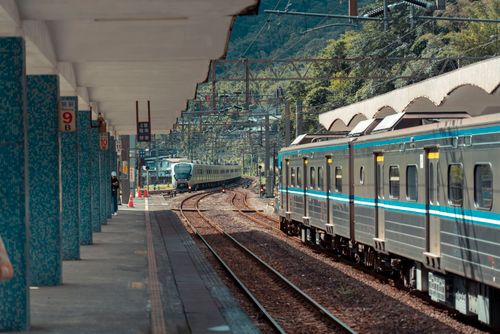 Free Passenger train approaching a scenic railway station surrounded by nature, capturing modern transport. Stock Photo