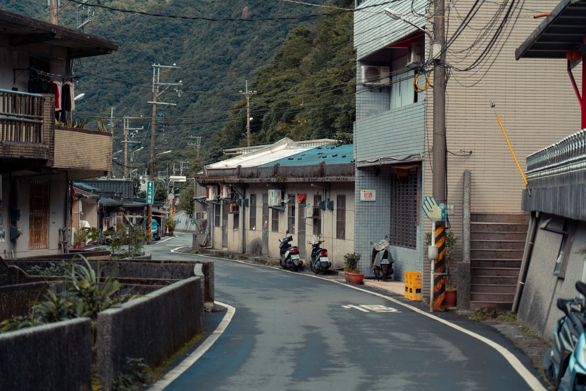 A rural cockfighting arena in Taiwan closed behind police tape, overcast sky and abandoned wooden benches