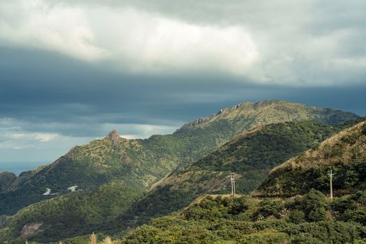 A breathtaking view of green hills and mountains under a cloudy sky, capturing the essence of nature.