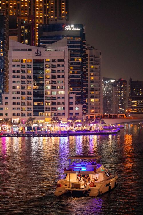 Free Experience the dazzling lights of Dubai Marina with a yacht reflecting in the sparkling waters during a serene night. Stock Photo